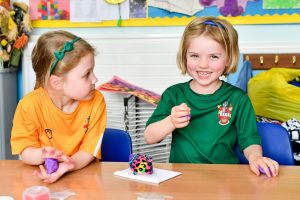 Reception pupils sat at desk playing with playdough and toys