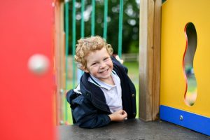 Reception pupil playing outdoors on play area
