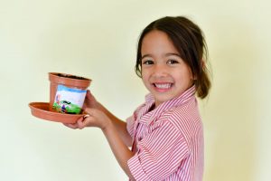 Reception pupil with decorated plant pot smiling